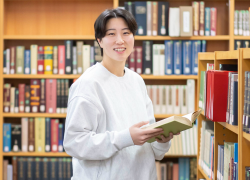 図書館で本を手に取る大学生
