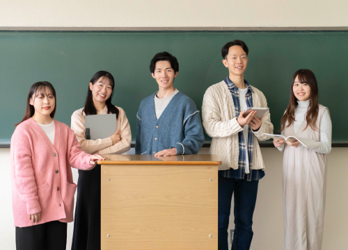 黒板の前に立つ大学生